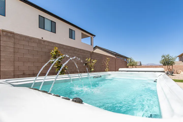 Swim spa with water features, surrounded by a block privacy fence