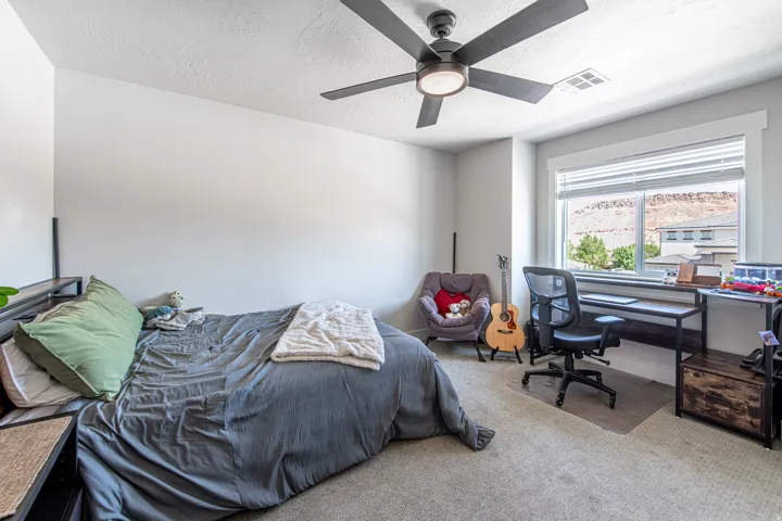 Bedroom featuring neutral wall paint, light-colored carpeting, a ceiling fan with integrated lighting, a large window with blinds, and white trim