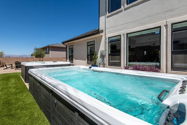 Backyard featuring a swim spa, an additional hot tub, and artificial turf