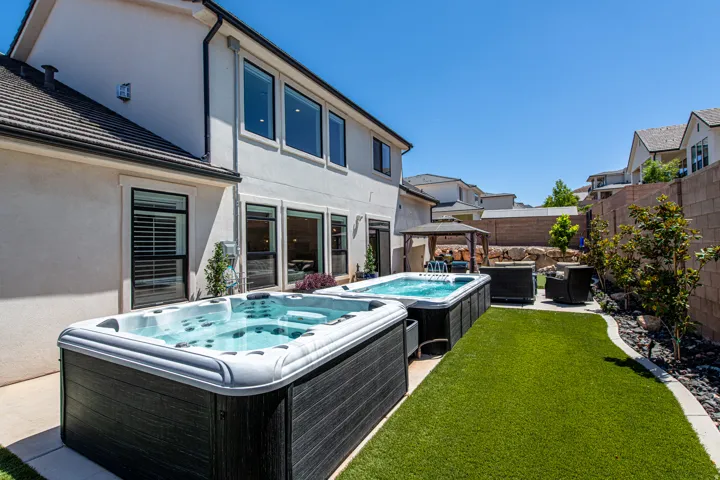 Backyard featuring two built-in spas, a gazebo, artificial turf, and a rock garden area