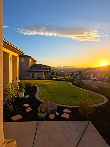Expansive outdoor space featuring a contoured lawn, decorative rock landscaping, and a concrete patio