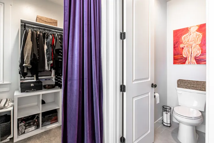 Walk-in closet featuring white shelving units and clothing rods