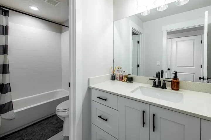 Bathroom featuring a white vanity with a quartz-finish countertop, undermount sink, and matte black fixtures