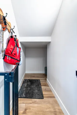 Hallway featuring wood-finish flooring and white trim