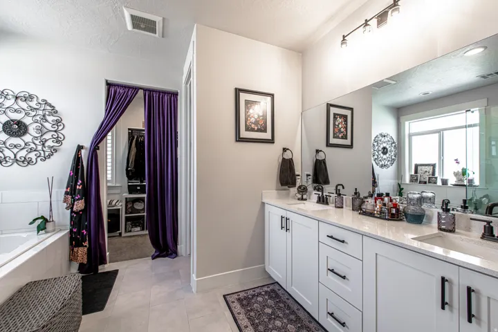 Dual vanity with white cabinetry and quartz countertops, featuring an integrated oversized mirror and contemporary track lighting