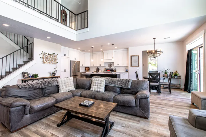 Open-concept living space featuring wood-finish flooring, a two-story ceiling, and a prominent staircase with metal railings