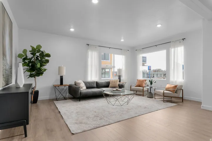 Spacious living area featuring light wood-finish flooring, recessed lighting, and expansive windows