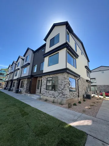Contemporary exterior featuring white and dark gray siding, an accent brick facade, a concrete walkway, and a landscaped rock garden