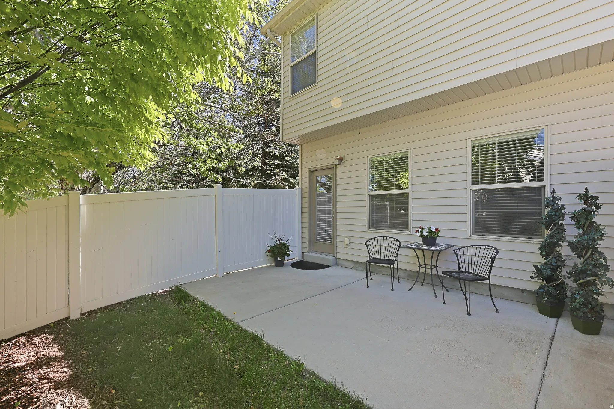 Concrete patio with a white vinyl privacy fence and a rear exterior door