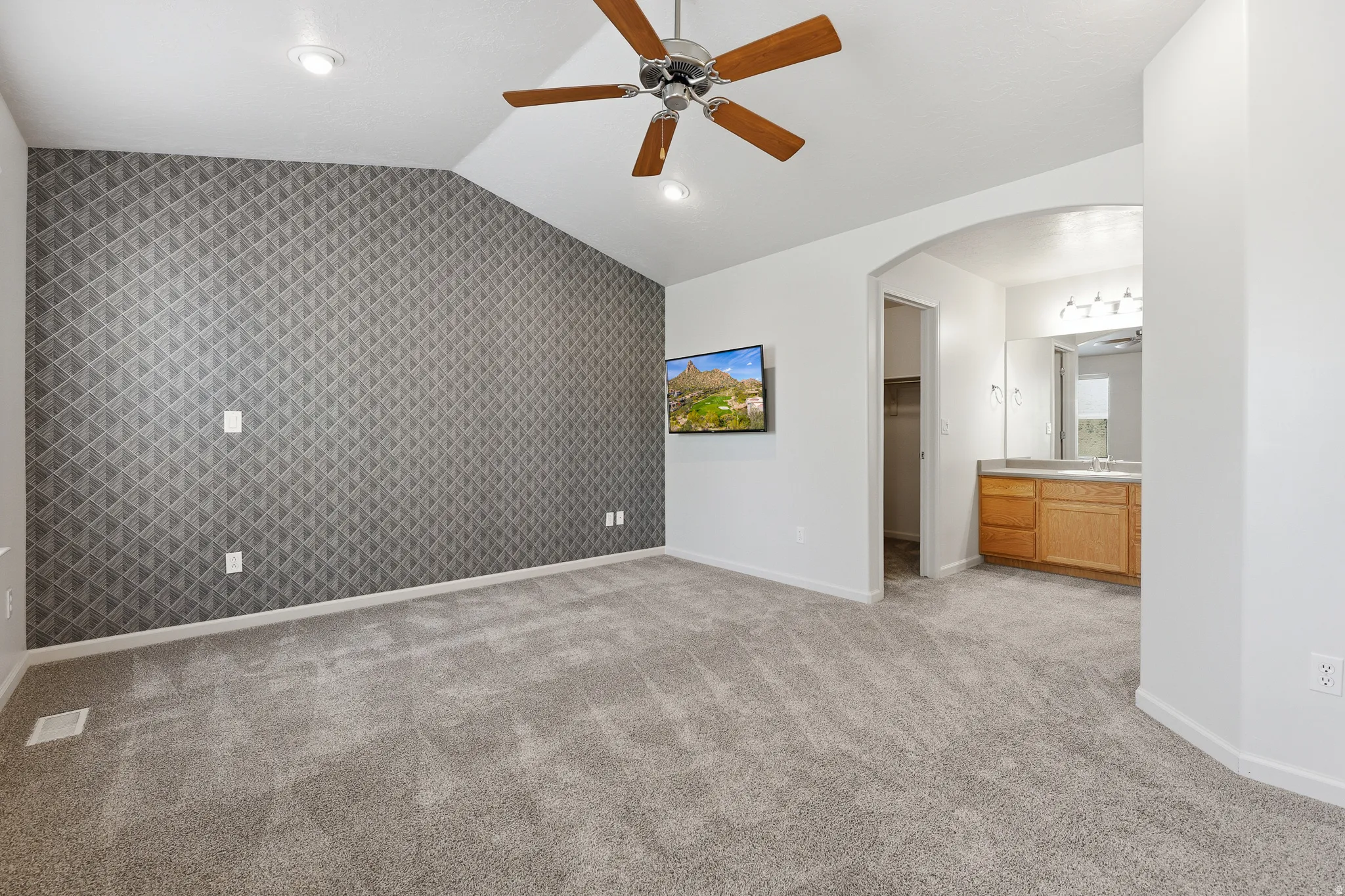 Spacious room featuring vaulted ceilings, recessed lighting, and a ceiling fan