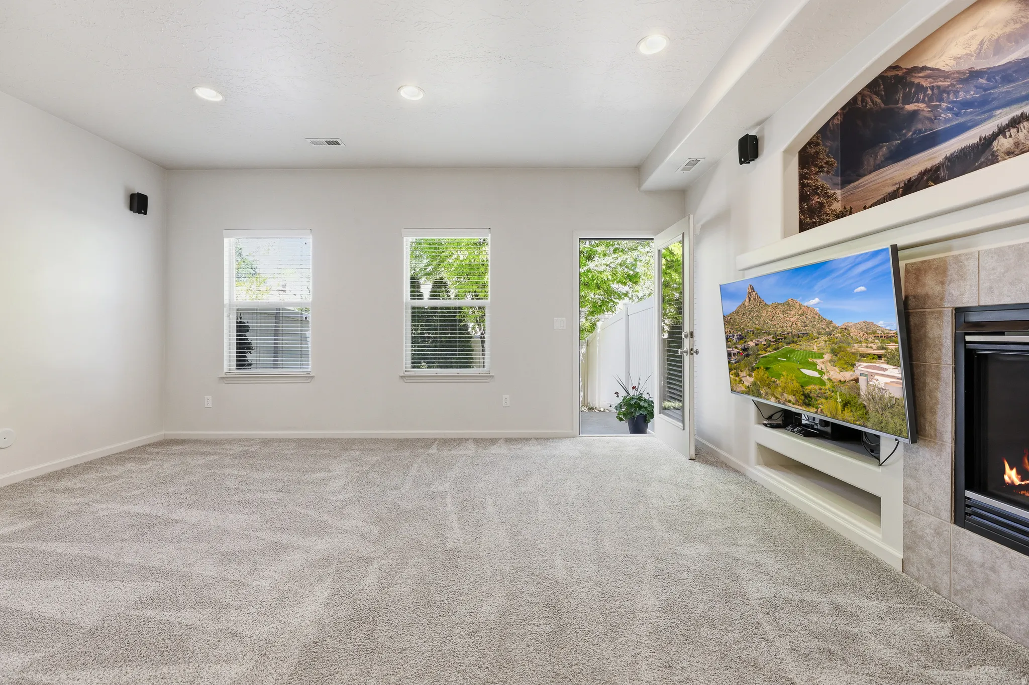 Spacious living area featuring light-toned carpeting, recessed ceiling lighting, and multiple windows with blinds