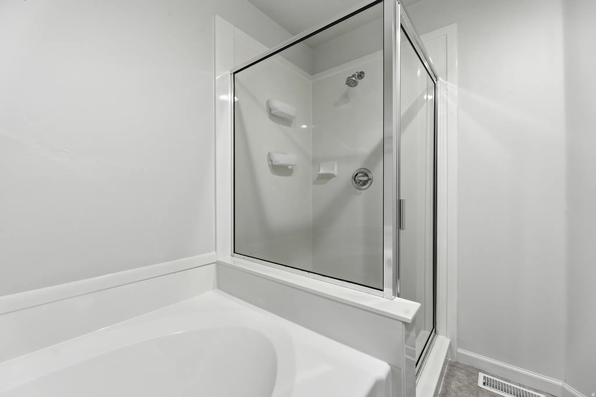 Bathroom featuring a glass-enclosed shower with a chrome showerhead and control, white wall surround, and an integrated bathtub