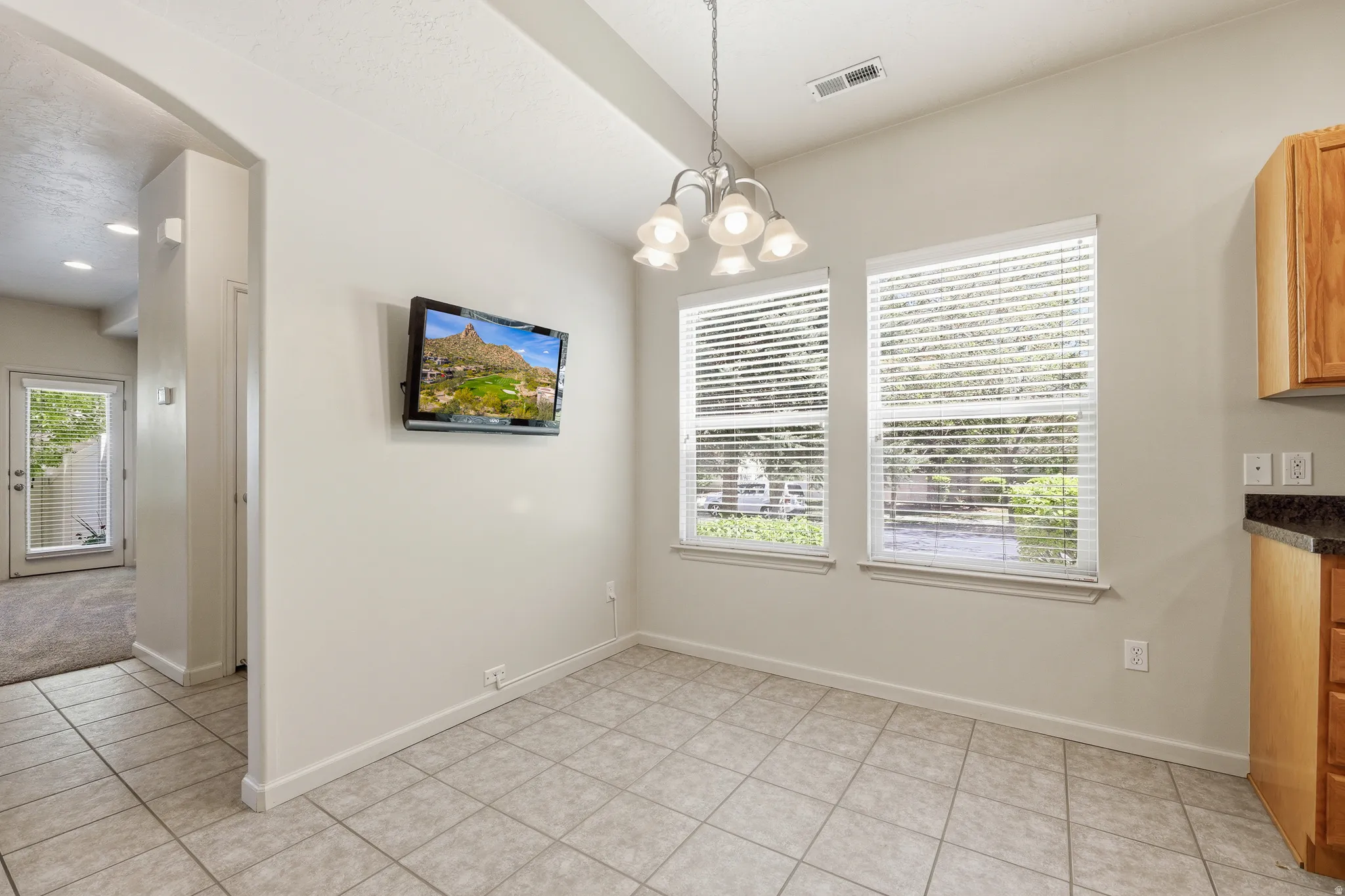 Dining area featuring tile flooring, a multi-light chandelier, and twin windows with blinds