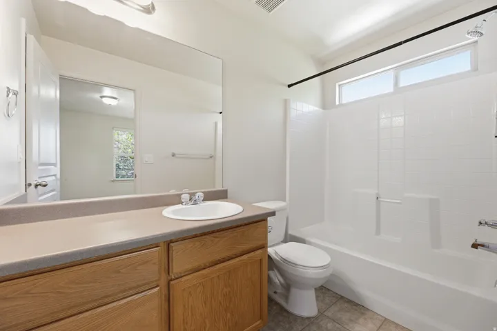 Bathroom featuring a wood-finish vanity with an integrated sink and a large wall-mounted mirror