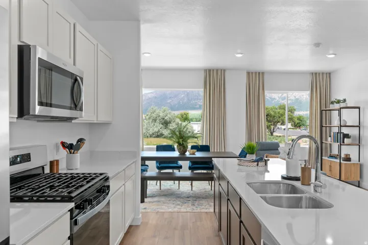 Modern kitchen featuring light-toned cabinetry, stainless steel appliances, and an expansive island with a dual-basin sink