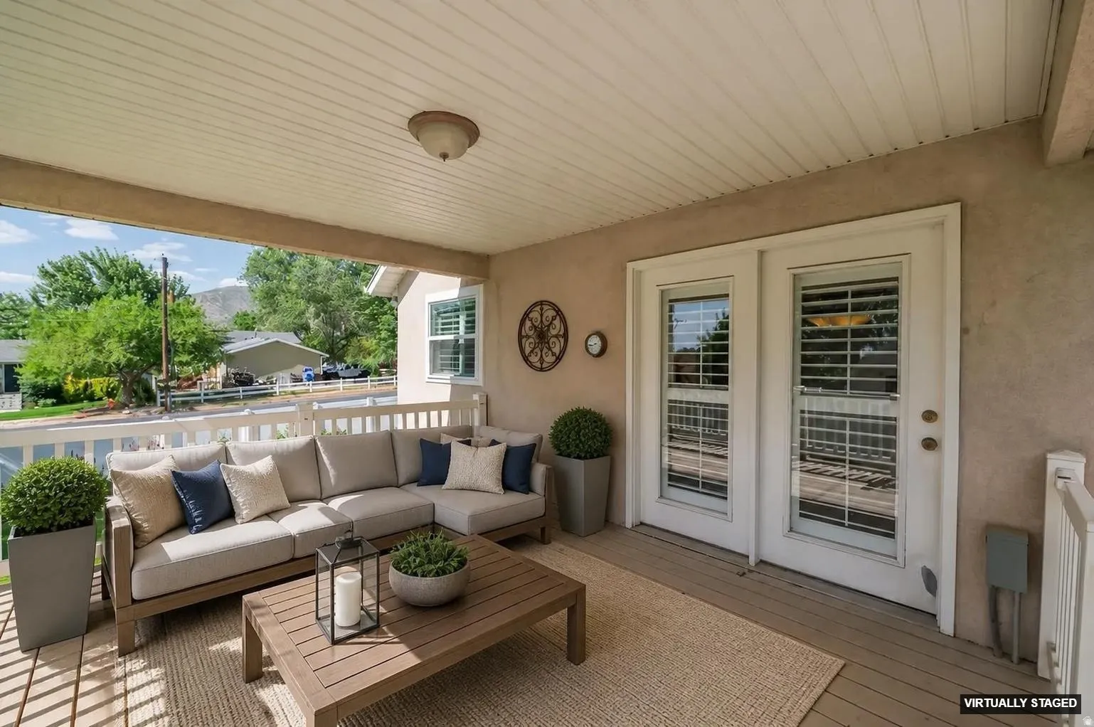 Covered outdoor patio featuring white wood-finish decking, a paneled ceiling, and double glass-paneled doors
