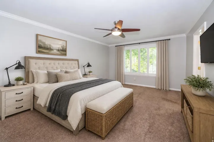 Crown molding, overhead ceiling fan with lighting, large bay window, wall-mounted television, and wood-finish media console