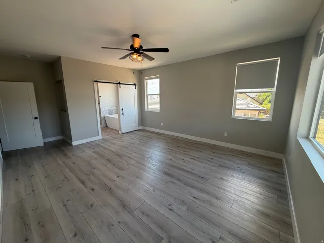 Spacious room featuring light wood-finish flooring, neutral wall tones, and multiple windows with roller shades