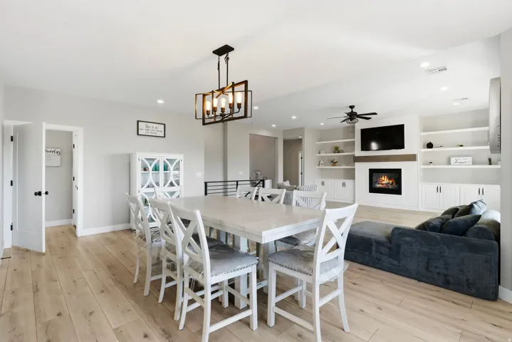 Open-concept living space featuring light wood-finish flooring, recessed lighting, and a modern rectangular chandelier