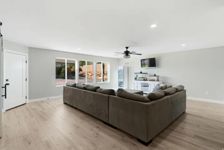 Bright living area featuring wood-finish flooring, a contemporary ceiling fan, and recessed lighting