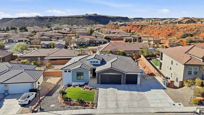 Contemporary residence featuring a two-car garage, contrasting exterior finishes, and a landscaped front yard with artificial turf