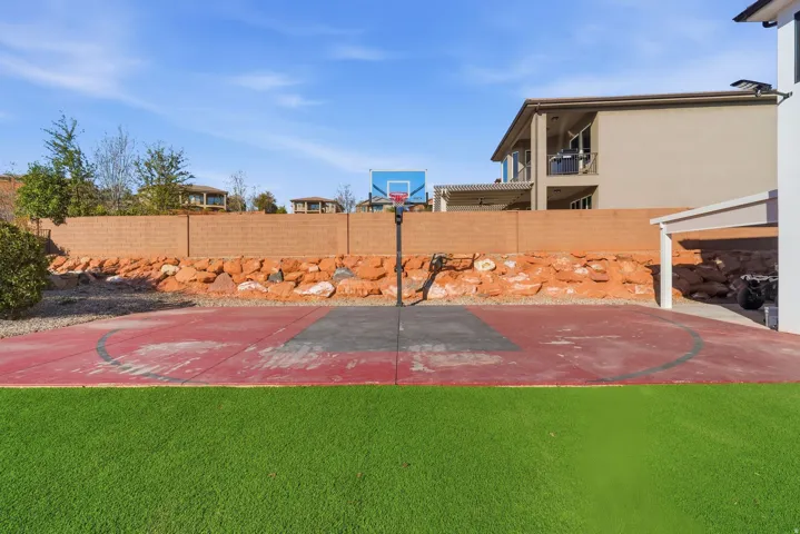 Outdoor sports court with painted red and gray surface, featuring an attached basketball hoop