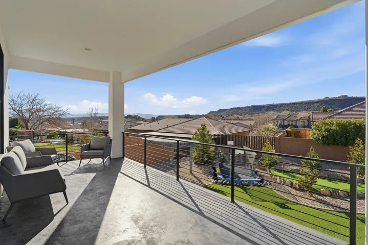 Expansive covered balcony featuring a concrete floor, recessed lighting, and black metal cable railings