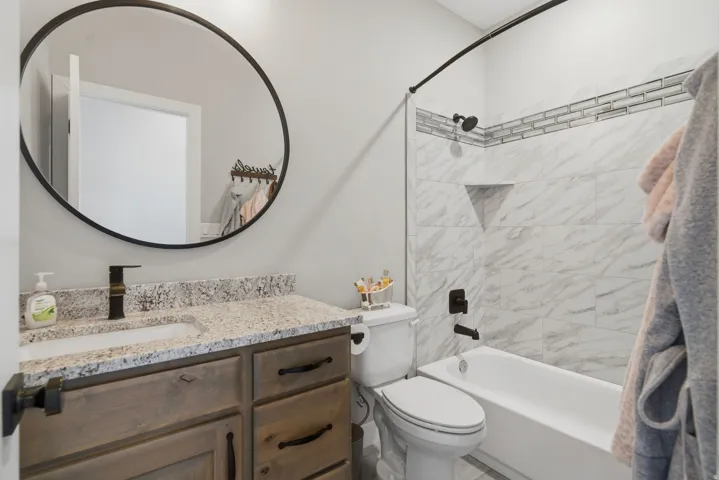 Bathroom featuring a wood-finish vanity with a granite countertop, undermount sink, and oil-rubbed bronze faucet