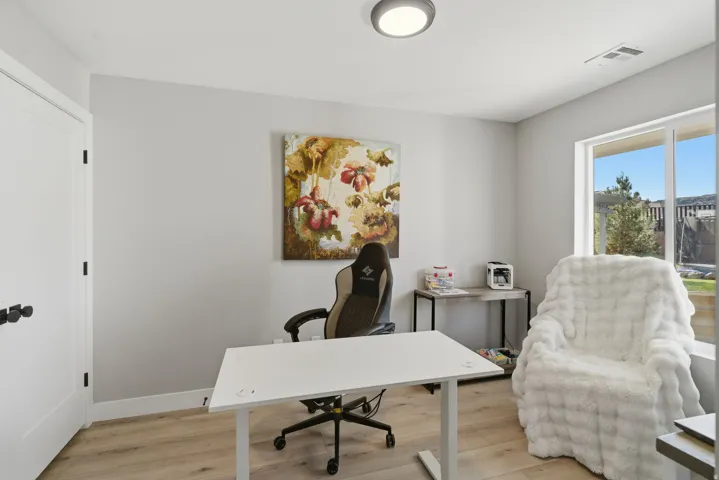 Bright room with wood-finish flooring, a large window, a modern ceiling light fixture, and white trim