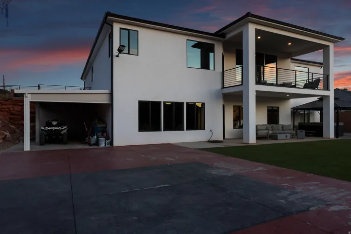 Contemporary two-story exterior featuring a ground-level patio and an upper-level balcony with metal railings