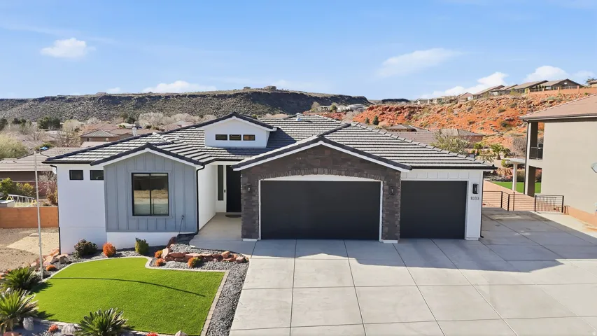 Contemporary exterior featuring a multi-paneled garage door, stacked stone accents, and a tile roof