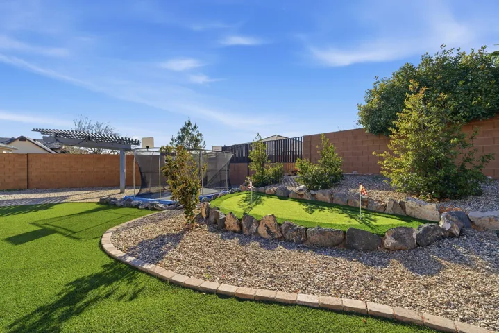 Expansive backyard featuring artificial turf, a putting green with rock edging, and gravel landscaping