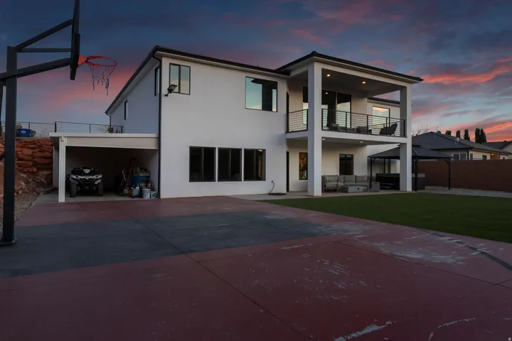 Modern stucco exterior with a covered upper-level balcony, a lower-level covered patio, and a covered carport