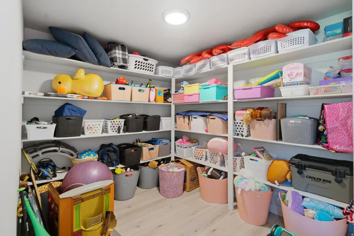 Dedicated storage room featuring extensive built-in shelving, recessed ceiling lighting, and light wood-finish flooring