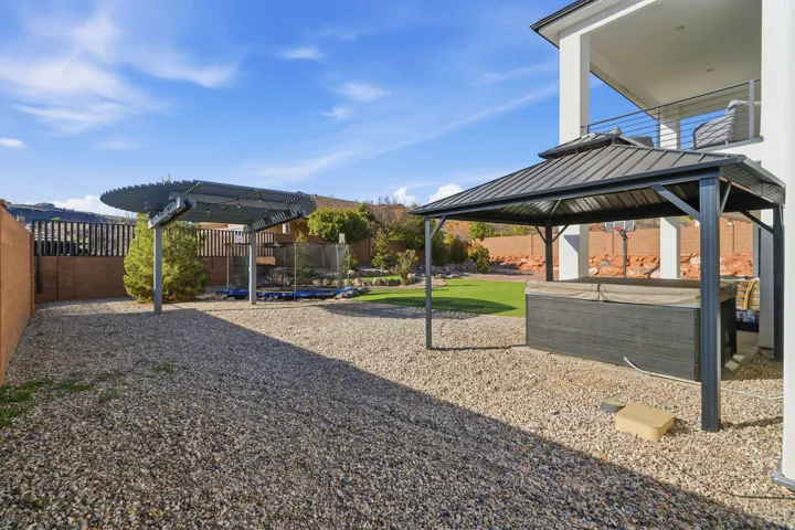Gravel hardscaping featuring a built-in gazebo over a spa and a separate pergola structure