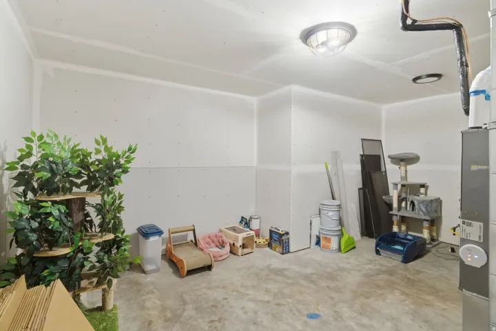 Unfinished utility room featuring a concrete floor, exposed ductwork, a ceiling-mounted light fixture, and drywall-ready walls