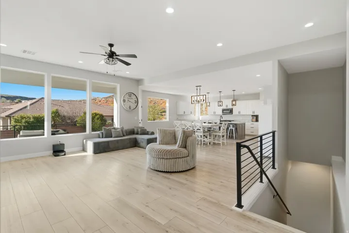 Open-concept living area with light wood-finish flooring, recessed lighting, and a contemporary ceiling fan