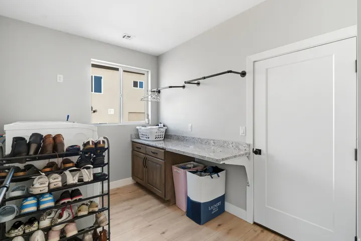 Dedicated laundry space featuring wood-finish flooring, a white-framed window, and light gray walls