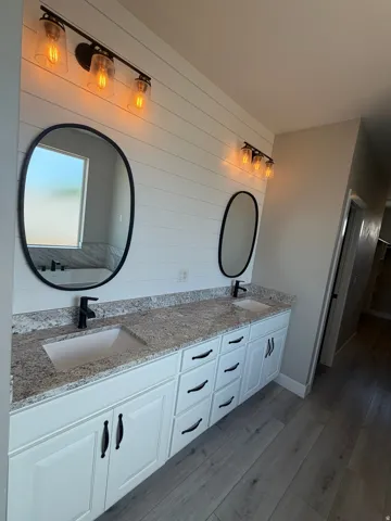 Double vanity with granite countertops, undermount sinks, and matte black fixtures