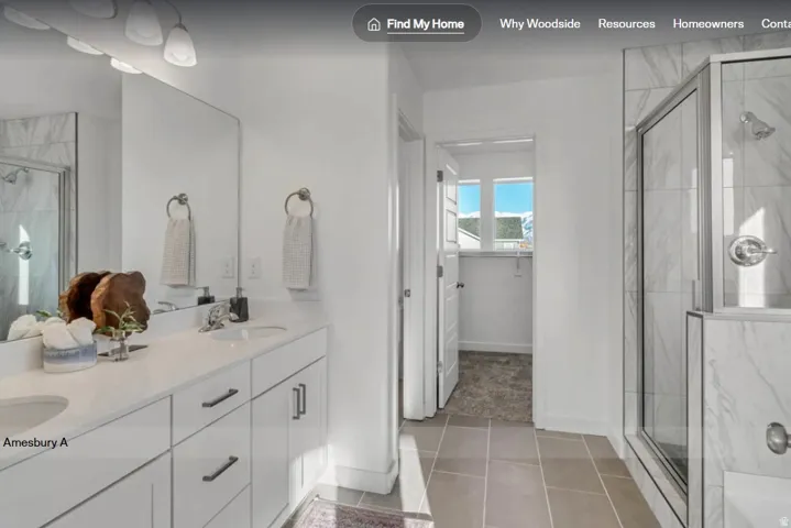 Bathroom featuring a spacious dual vanity with white cabinetry and integrated sinks, a walk-in shower with glass enclosure and tiled walls, and large format tile flooring. This picture is of another home