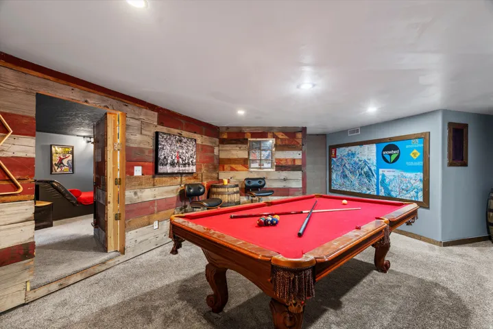 Entertainment space featuring a billiards table with a red felt surface, textured wood-finish wall paneling, recessed lighting, and carpet flooring