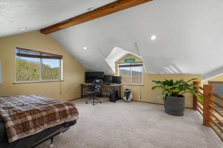 Carpeted loft space featuring exposed wood ceiling beams, sloped ceilings, recessed lighting, and wood railing
