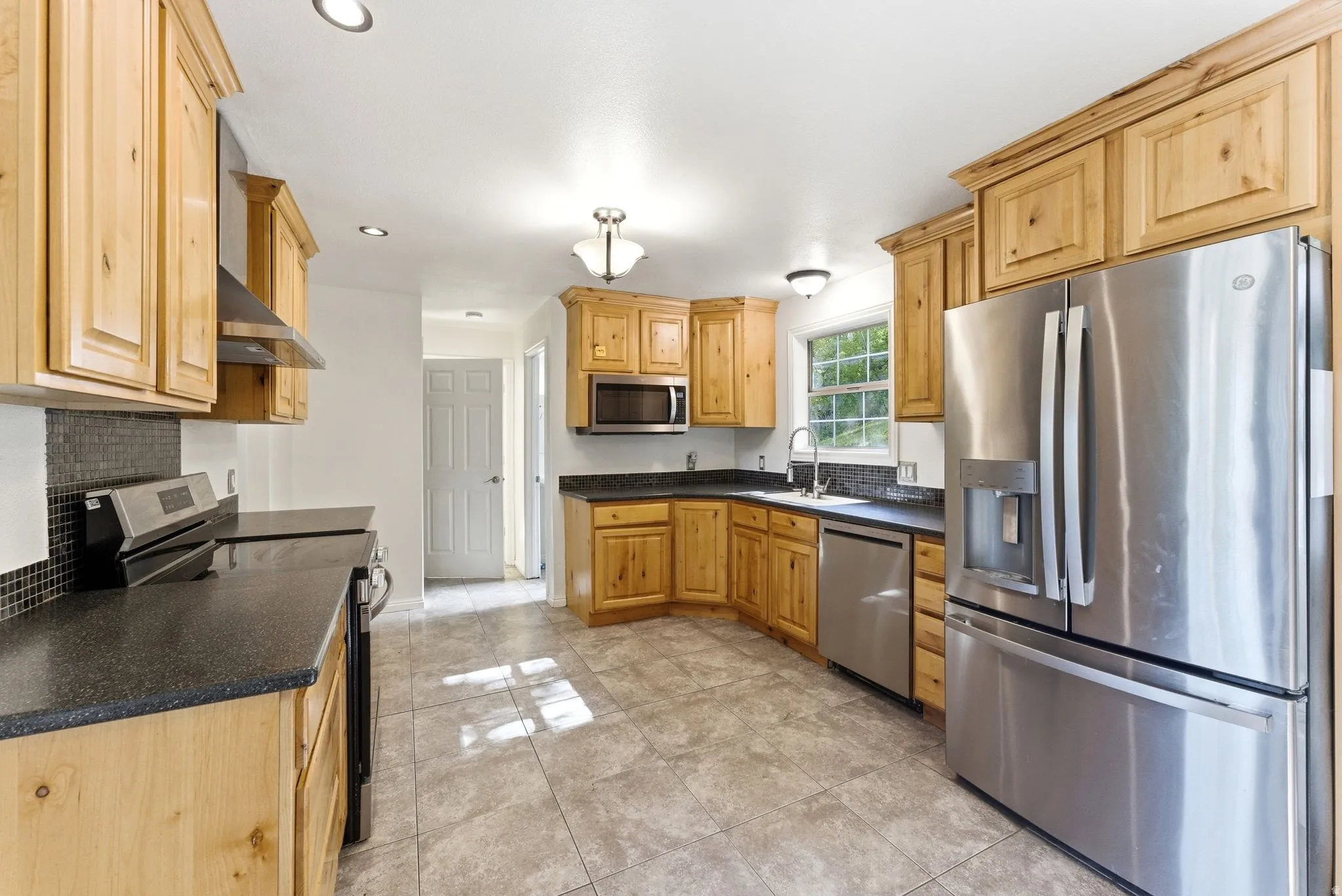 Kitchen featuring wood cabinetry, tile floors. Stainless refrigerator included
