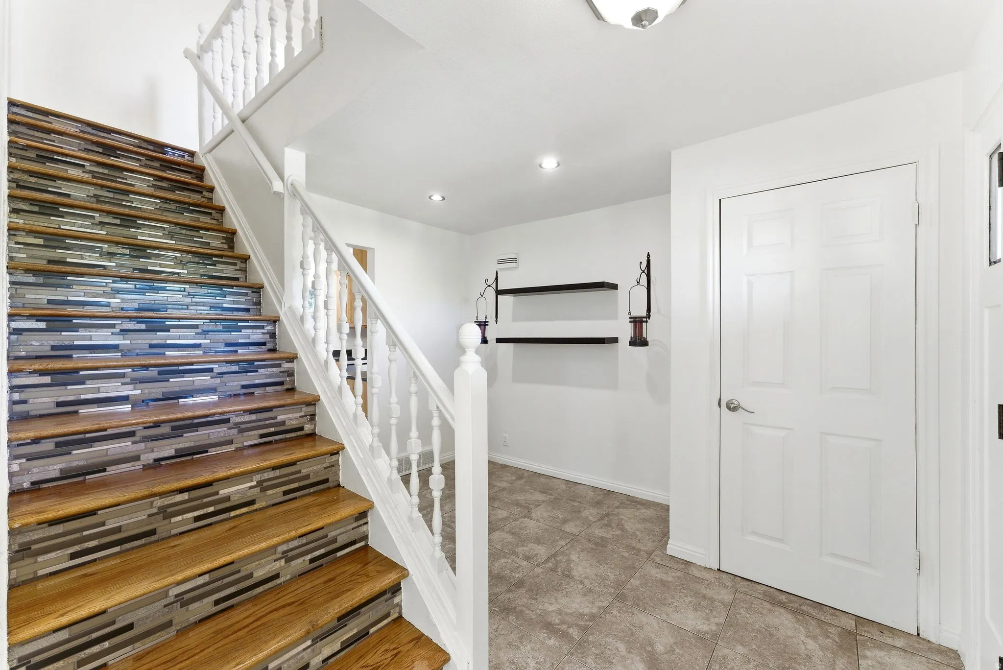 Hardwood staircase featuring decorative riser tiling and white balusters