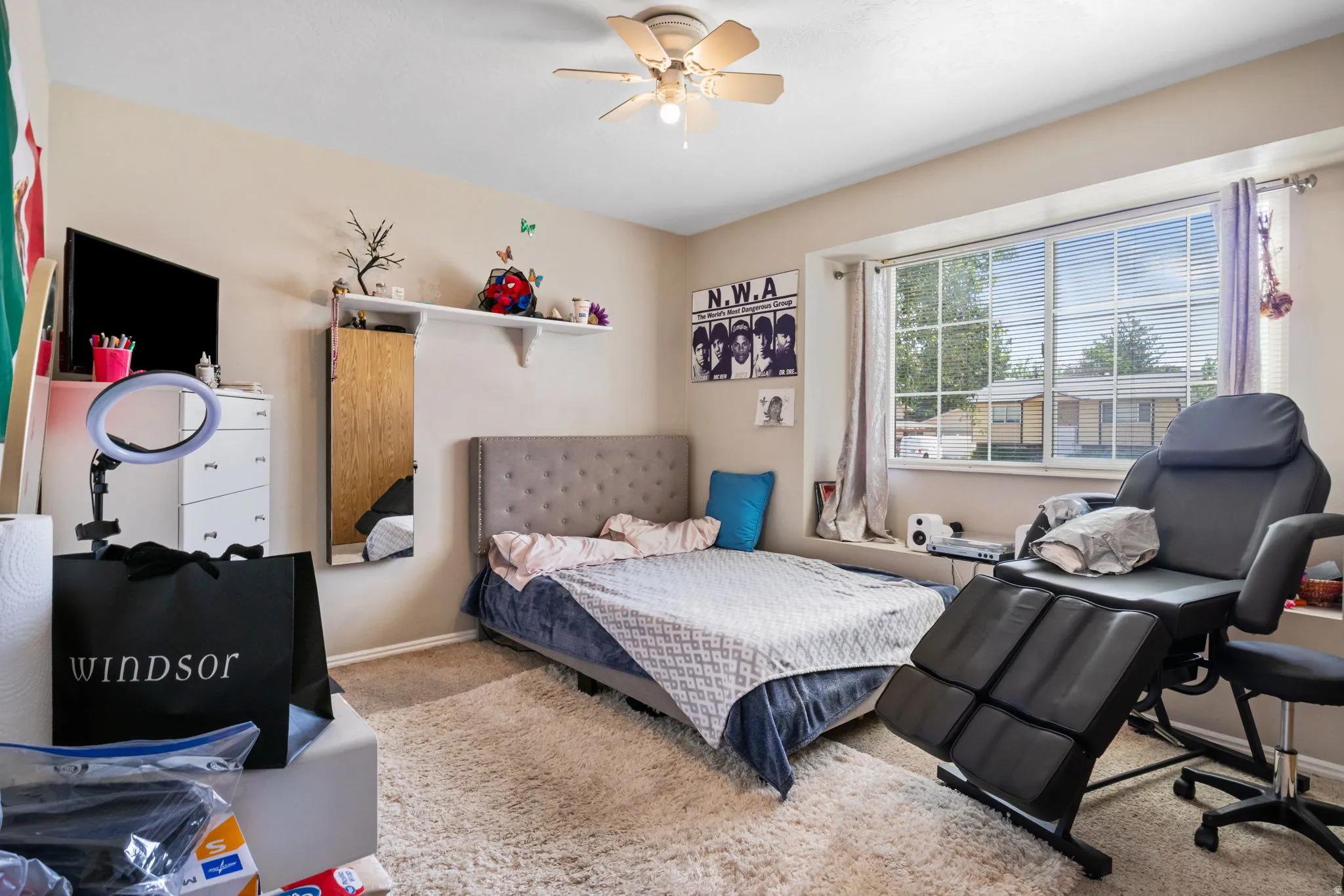 Bedroom featuring a ceiling fan, window with blinds, and light-toned walls