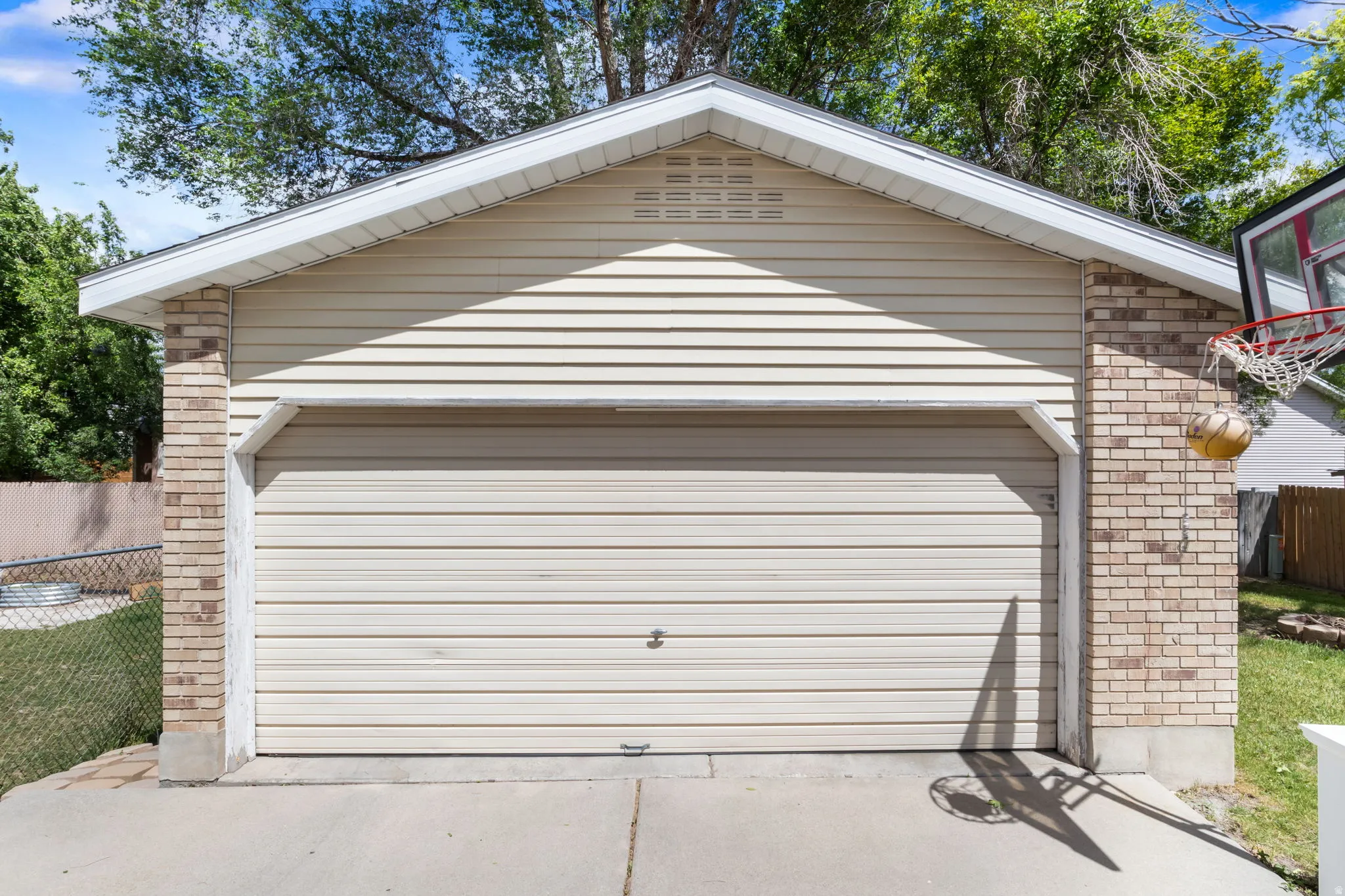 Attached garage featuring a beige horizontal siding exterior with light brick accents and a concrete driveway