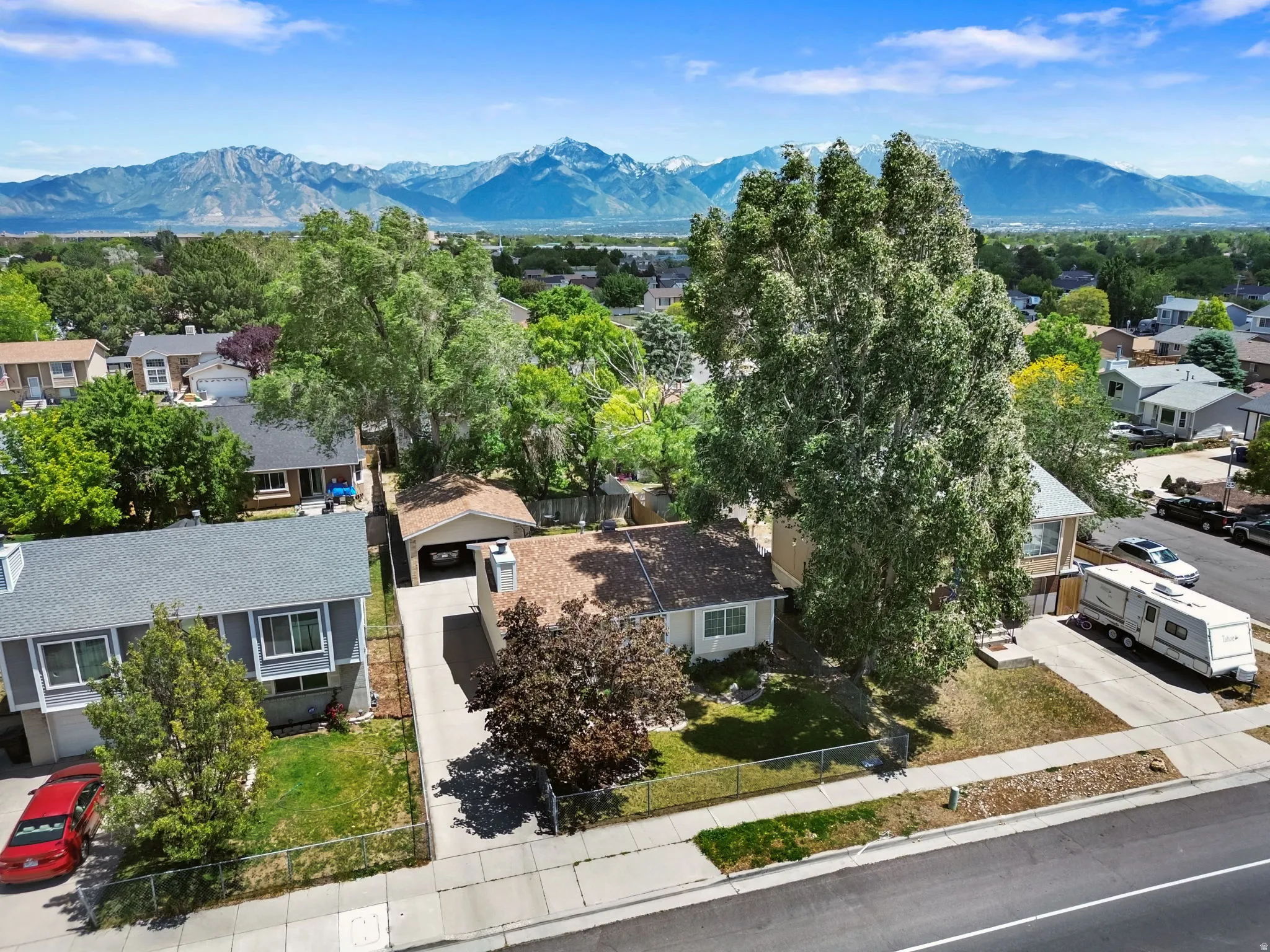 Single-family residence with an attached carport, featuring mature trees and a manicured lawn