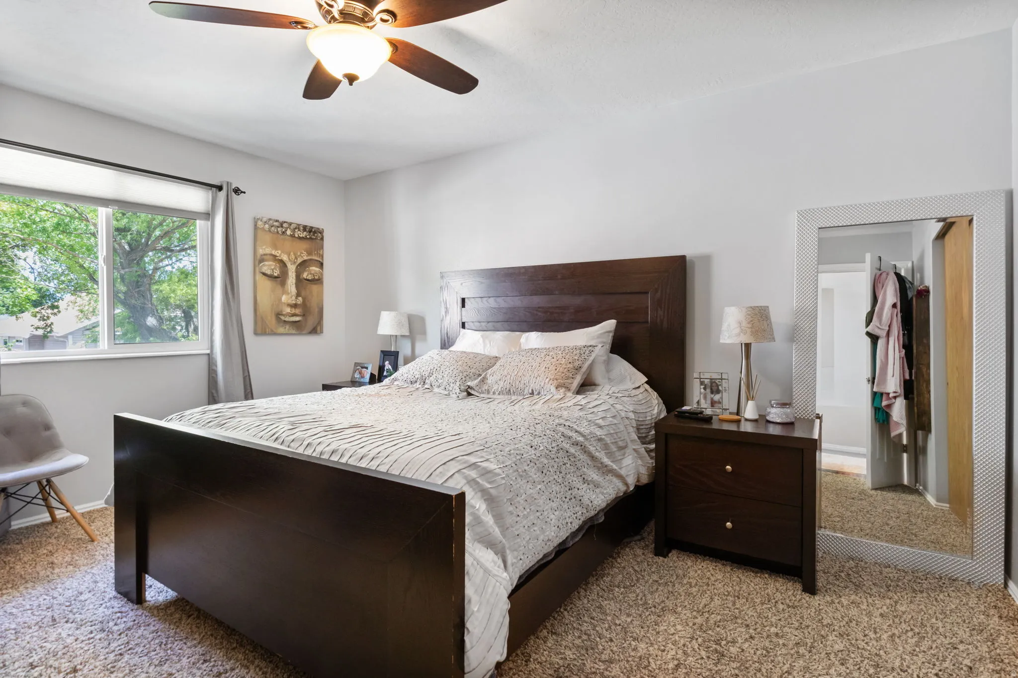 Bedroom featuring light neutral wall paint, a window with roller shade, a ceiling fan with integrated lighting, and carpet flooring