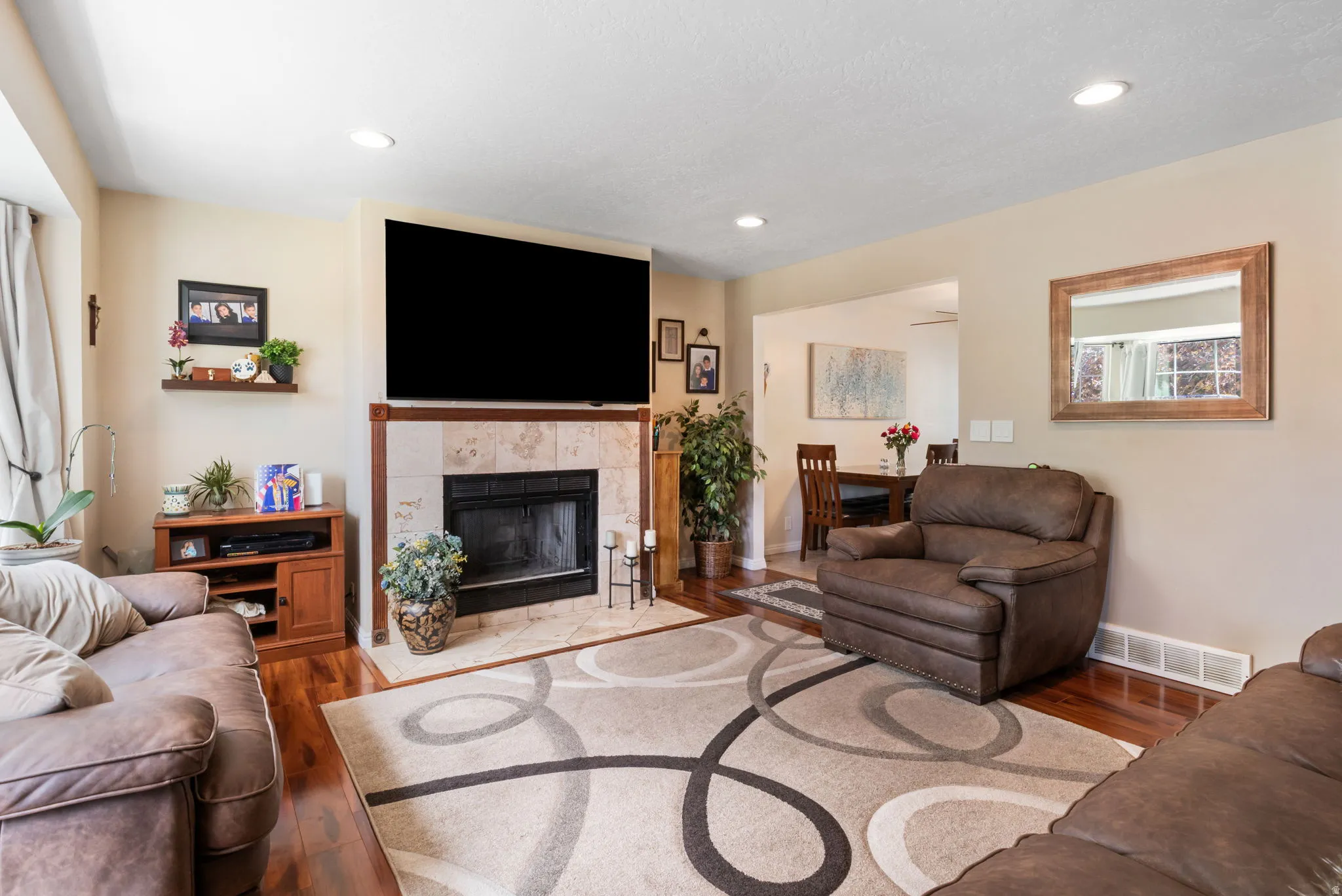 Living area featuring a tile-surround fireplace with a wood mantel, recessed lighting, and wood-finish flooring