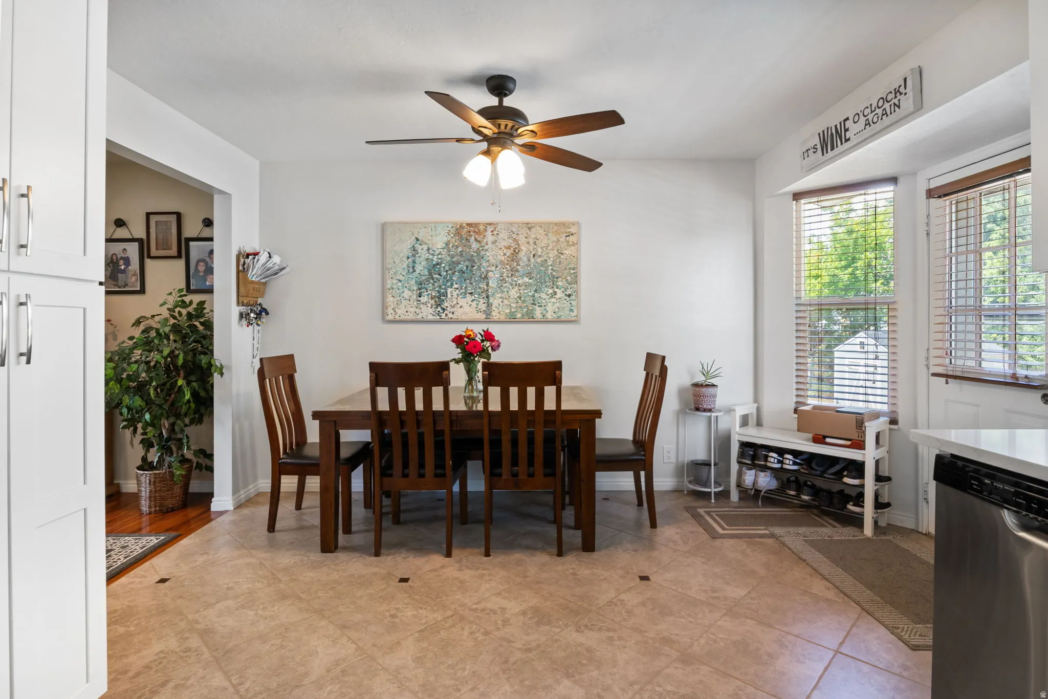 Dining area featuring neutral tile flooring, a dark wood-finish dining set, and a ceiling fan with integrated lighting